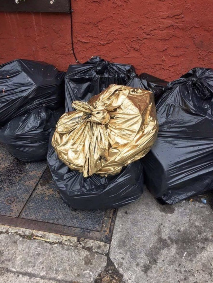 Sac poubelle doré posé sur des sac poubelles