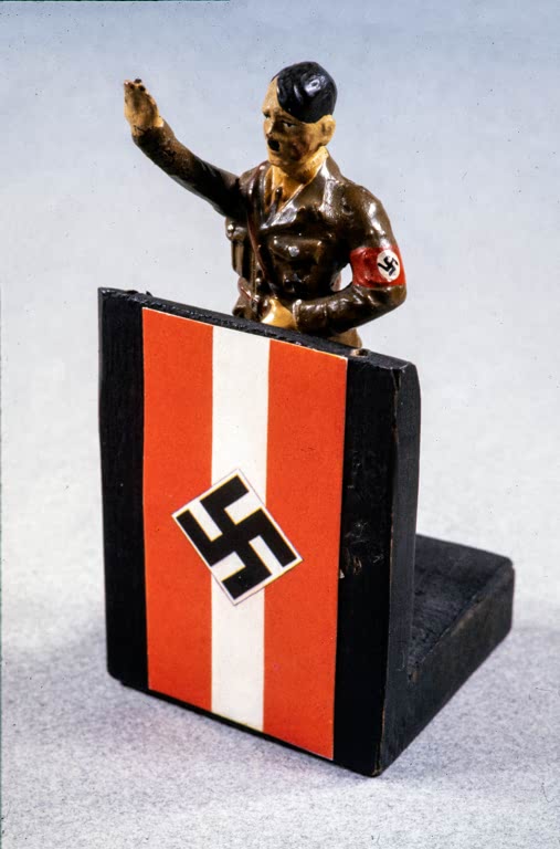 Figurine d'Adolf Hitler en salut nazi devant un présentoire nazi