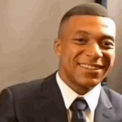 Kylian Mbappé qui sourit puis réalise qu'il ne faut pas