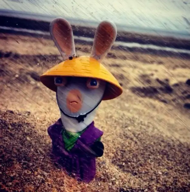 Un Lapin Crétin déguisé en samouraï avec un regard agressif sous la pluie