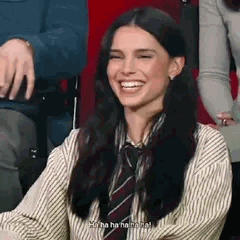 Une jeune femme tire la langue puis explose de rire