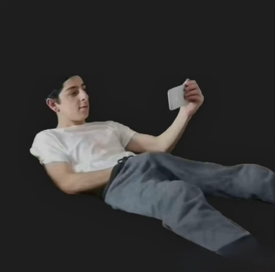 Jeune homme allongé regardant son téléphone avec la main dans le calebar/slip pour se branler/masturber