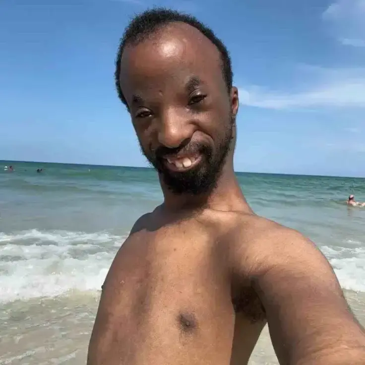 Un homme torse nu sourit sur la plage