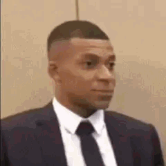 Kylian Mbappé pince les lèvres en costume dubitatif