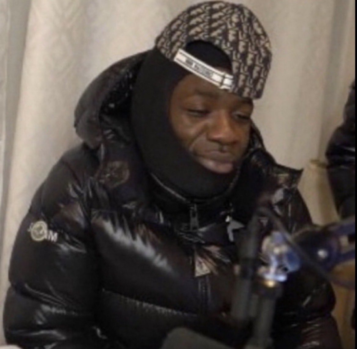 Gazo en doudoune et cagoule souriant les yeux mi-clos