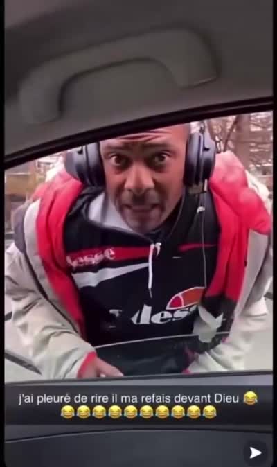 Un homme avec un casque demande de la monnaie à la vitre d'une voiture en bavant dans la voiture