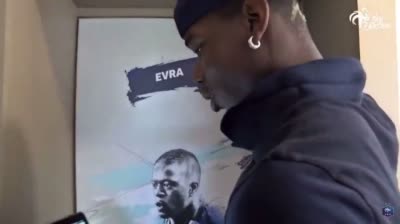 Paul Pogba devant la porte de  la chambre d'Evra pour le réveiller