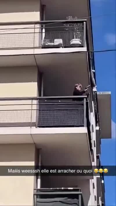snapchat - Blocus lycée, Femme sur un balcon qui vise la rue avec un pistolet