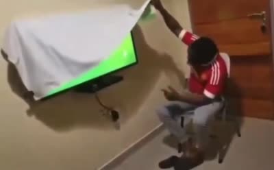 Homme soulève légerement le drap cachant le match de foot puis se cache le visage