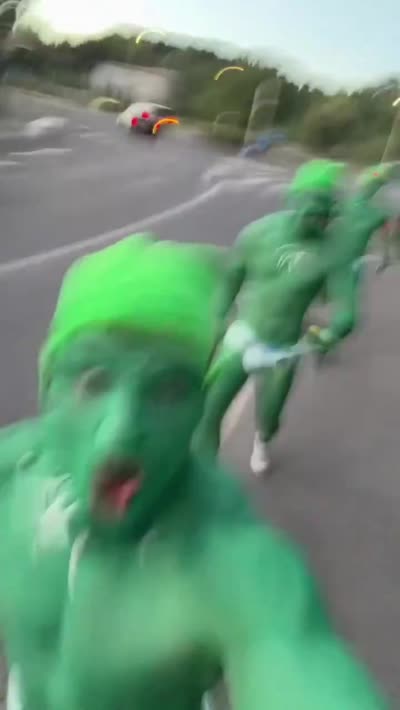 Des hommes déguisés en gobelins verts courent dans la rue en criant : Macron, t'es où ?! Viens là, qu'on t'attrape !